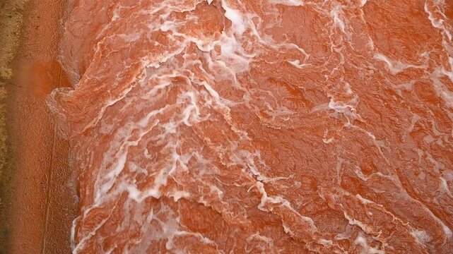 Abstract red water texture with foam patterns and swirling waves, natural background surface with copy space. Abstract orange-red texture from an iron and steel manufactory, molten metal or industrial