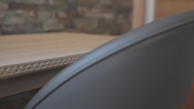 Macro view of a modern dark gray leather chair backrest next to a carved wooden table edge