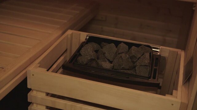 Empty wooden sauna with a heater and hot stones for steam, promoting relaxation and wellness