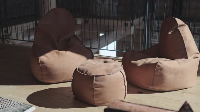 Modern leather beanbag chairs and pouf sitting on a wooden floor in a sunny loft apartment