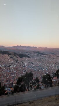 Breathtaking panoramic view of La Paz city canyon at sunset with majestic Illimani mountain background, impressive urban landscape and real estate density during golden hour in Bolivia