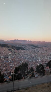 Breathtaking panoramic view of La Paz city canyon at sunset with majestic Illimani mountain background, impressive urban landscape and real estate density during golden hour in Bolivia