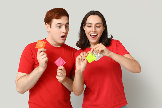 Young couple with condoms on grey background. Safe sex concept