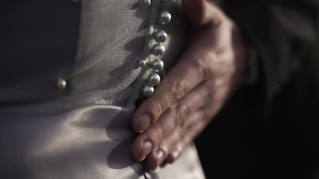 Man gently touches woman's back and runs his palm over the buttons of her gray dress.