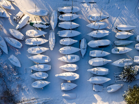 Aerial view of many sailboats parked on land and covered in thick white snow during a sunny winter day Trakai, Vilnius County, Lithuania.