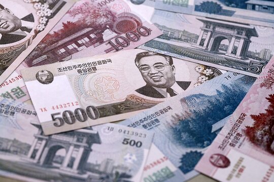 North Korean won money bills pile on table. North Korea banknotes of KPW currency close up.