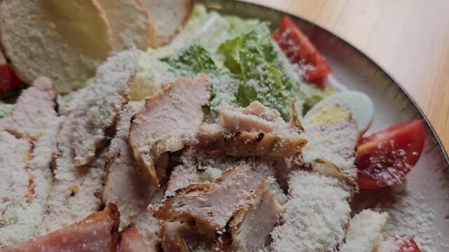 Caesar salad Traditional caesar salad in a white bowl with leaves and a sauce boat and parmesan. Selected focus.