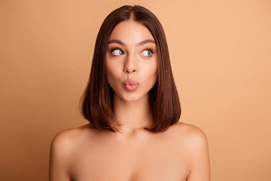 Natural beauty portrait of a young woman with a sleek bob hairstyle on a beige background
