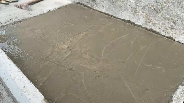 Concrete floor repair area with trowel and work gloves on site closeup