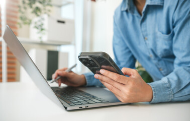 Fototapeta premium Mobile business professional using smartphone and laptop person managing digital communication remote workflow online productivity and modern multitasking operations.