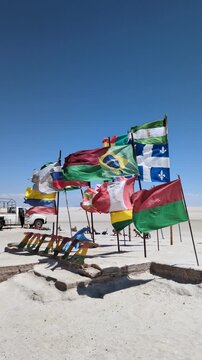 International flags waving at the famous flag monument plaza in Salar de Uyuni salt flat under clear blue sky, iconic travel landmark and tourism destination in Altiplano highland, Bolivia