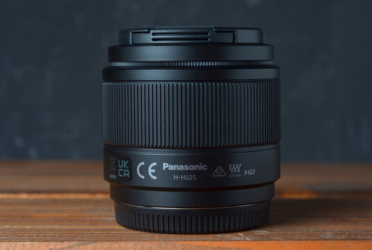 PERPIGNAN, FRANCE - MAY 12, 2026: A Panasonic Lumix G 25mm f1.7 ASPH (Model H-H025) mirrorless lens on a wooden surface. This fast prime lens is a popular choice for Micro Four Thirds system cameras.