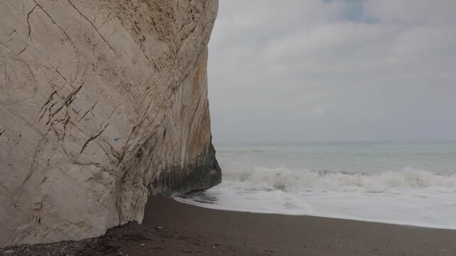Rocky beach and sea waves under cloudy sky on a misty morning