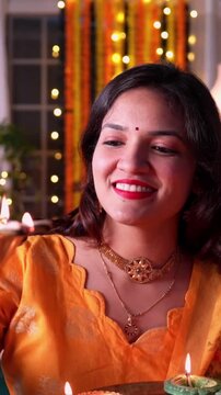 Joyful Indian Asian married couple dressed in traditional attire lighting diya or samai to celebrate Diwali festival at night, surrounded by festive decor, vibrant lighting in a beautifully adorned