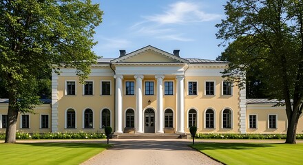 Obraz premium Elegant historic building with columns and manicured lawn under a blue sky