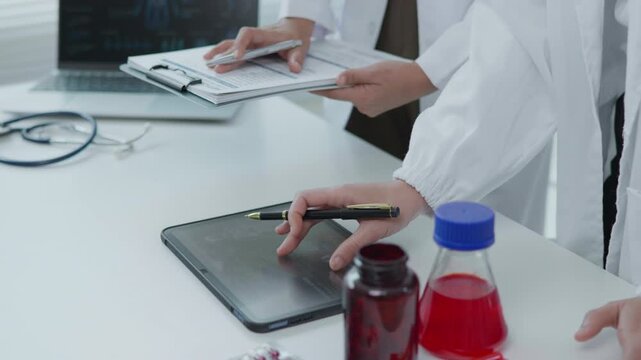 Medical Professionals Reviewing Tablet Treatment Chart in Clinical Office Healthcare Environment Focus on Technology and Collaboration