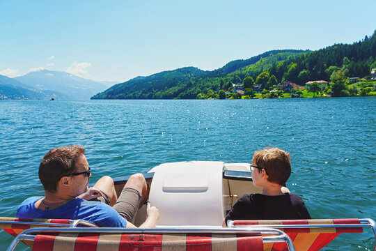 father and son rides a catamaran on vacation. Mountain lake. Family outing.