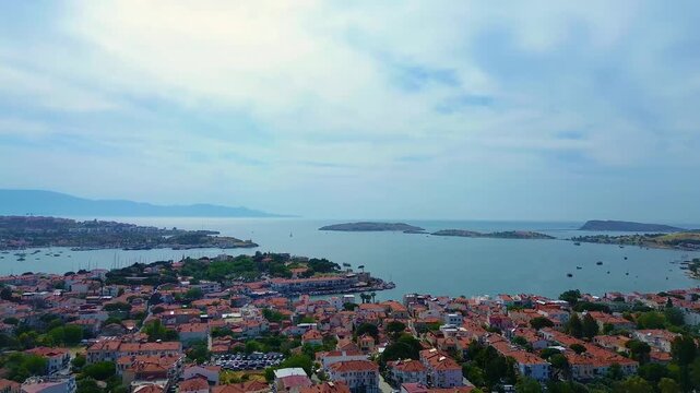 Aerial view of a coastal town with terracotta roofs and a blue bay dotted with boats. Turkey, Izmir, Eski Foca