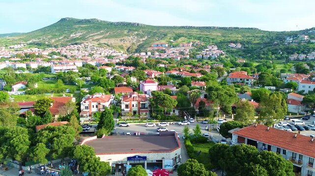 Scenic aerial view of a Mediterranean coastal town nestled against a green mountain. Turkey, Izmir, Eski Foca