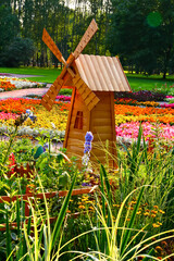 Naklejka premium Wooden Windmill in Vibrant Flower Garden on a Sunny Day