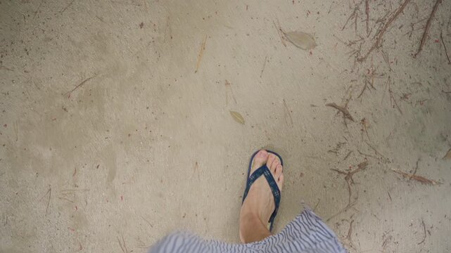 First person view of woman walking in sandals on sandy path