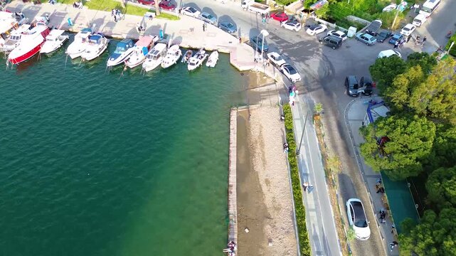 Aerial view of a bustling harbor with boats docked and cars parked along the waterfront. Turkey, Izmir, Eski Foca