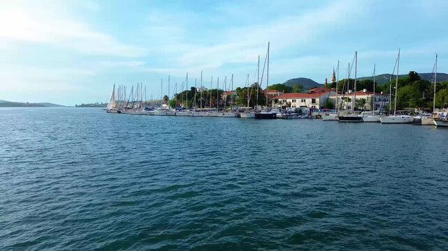 Serene harbor with sailboats and coastal town under blue sky. Turkey, Izmir, Eski Foca