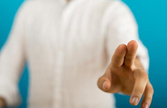 Hand reaching forward in gesture, isolated on blue. Focus, choice, decision concept.