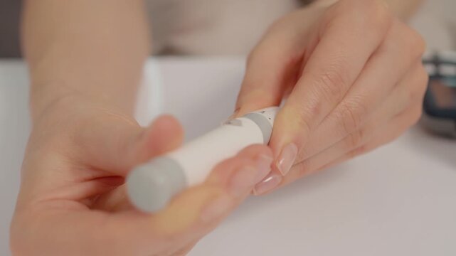 A woman prepares a finger pricking device before measuring her blood sugar levels. This process helps manage diabetes and monitor glucose levels at home.