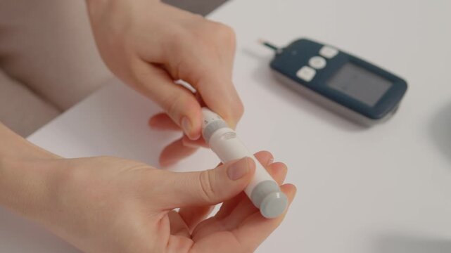 A woman holds a finger pricking device to check her blood sugar levels. She is engaged in managing her health and monitoring diabetes at home.
