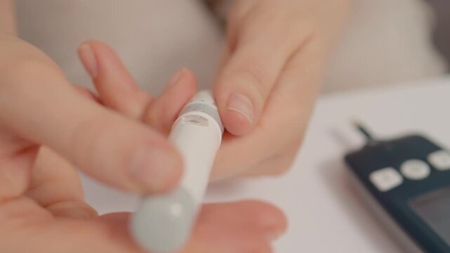 A woman holds a finger pricking device in her hands to check her blood sugar levels. She prepares to test for high glucose due to diabetes management.