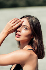 Naklejka premium Young woman portrait in sunlight shielding her eyes with hand, natural beauty model outdoors with glowing skin and relaxed expression