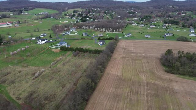 Highway rural interface along US15 near Elmer Derr Rd with open fields, scattered houses, flowering tree clusters marking semirural edge of western Frederick highlights mixed vegetation, MD