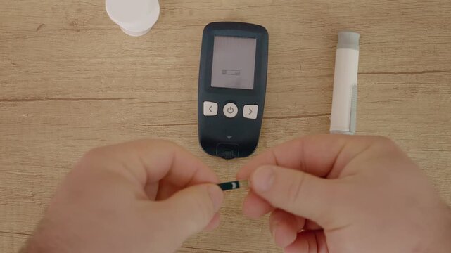 A man prepares to check his blood sugar level. He inserts a test strip into a glucometer to measure glucose. This is important for managing diabetes.