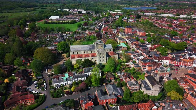 Aerial drone view over Romsey Abbey and the surrounding historic town centre, with rooftops, streets, trees and countryside in Hampshire, England.