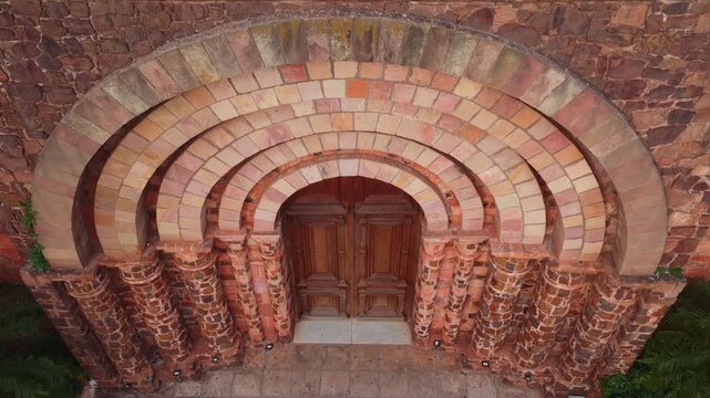 Top down close up aerial view of layered brick arch and wooden doors at historical church landmark in Villarrica Paraguay