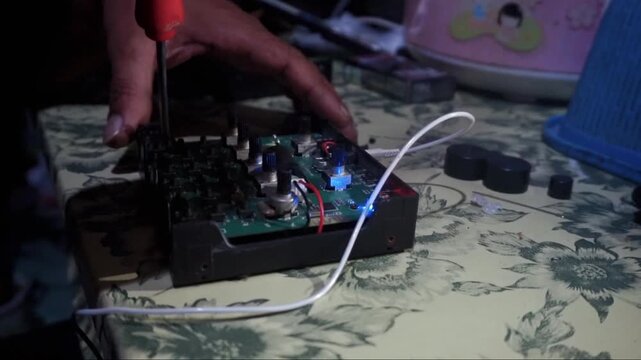 Hand adjusts circuit board with screwdriver