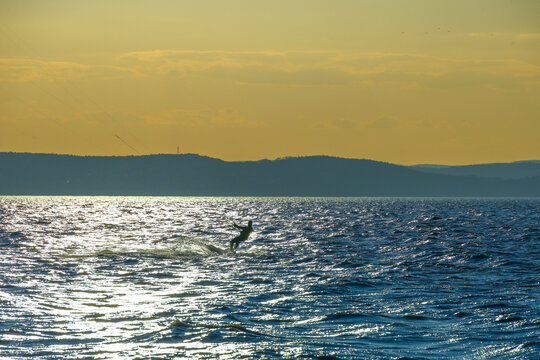 kitesurfer on lake balaton gliding across sunlit water with warm sunset tones and a wide calm horizon above the open lake surface