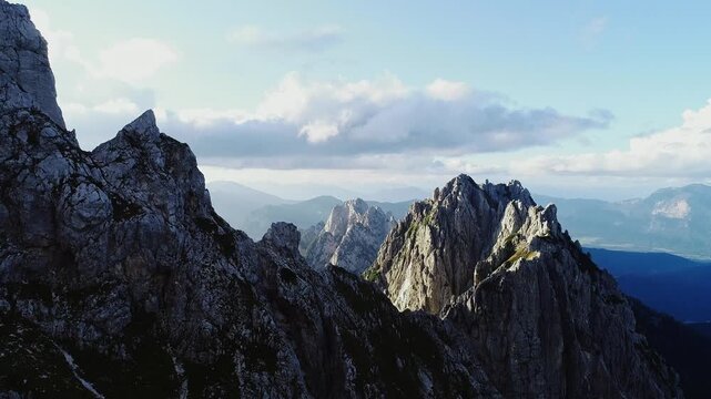 Fast drone flyby reveals hiker on cliff edge, vast alpine range in golden light