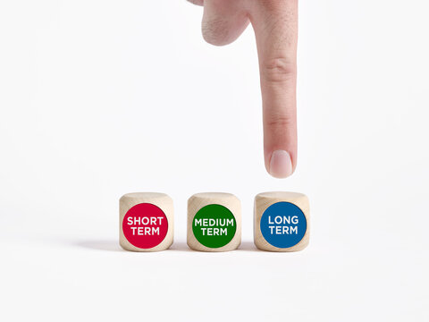 Hand pointing at long term wooden block in decision making