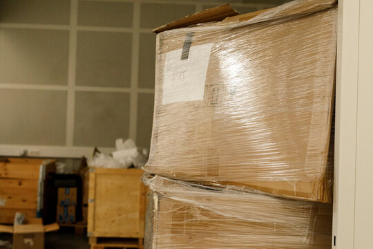 Cardboard packages are stacked and secured with shrink wrap in a storage facility