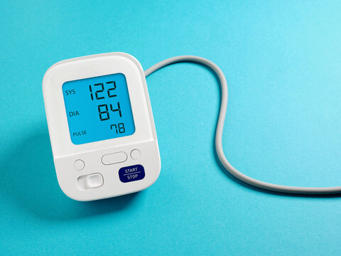 Digital blood pressure monitor showing healthy results on a vibrant blue background, home healthcare and hypertension management concept