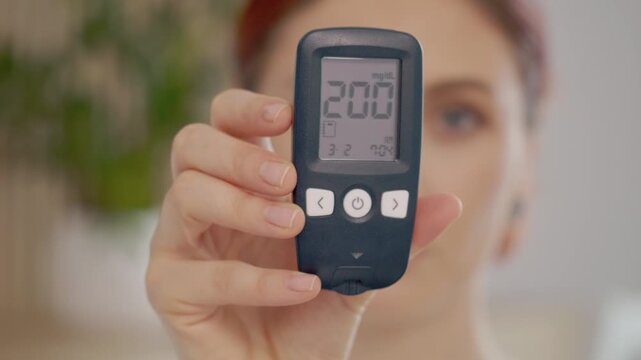 A woman holds a glucometer while showing a reading of 200 mg dL. This reading indicates a very high blood sugar level, which can be a concern for health.