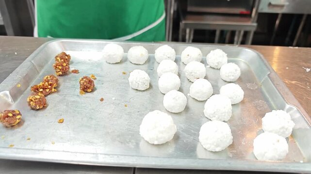 Shaping raw sago dough balls with sweet peanut stuffing on a tray.