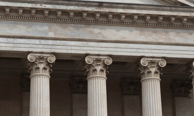 Obraz premium three worn neoclassical columns supporting faded entablature intricate details soft diffused sunlight casting subtle