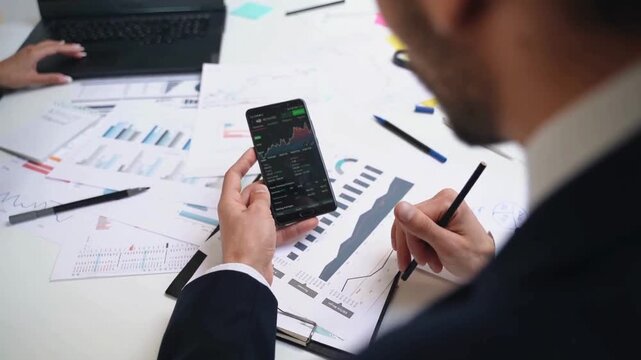 Stock market trader analyzing financial charts on smartphone, professional investor tracking crypto data, business analyst reviewing growth reports