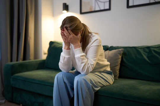 Woman sitting in emotional exhaustion at home