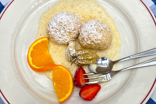 Gourmet Dessert Plate with Orange Slices, Strawberries, and Sugar-Dusted Dumplings
