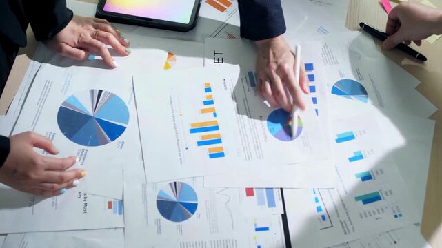 Professional business team analyzing financial data charts, corporate marketing strategy meeting with paper documents, hands pointing at growth statistics