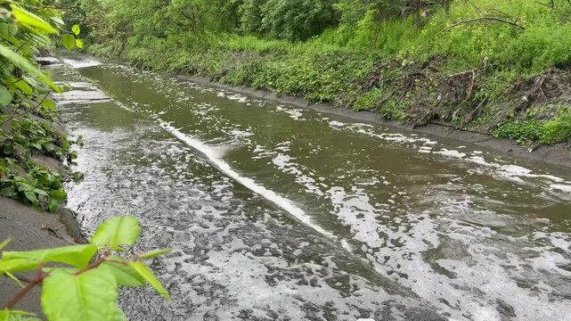 Massive urban wastewater discharge flowing from municipal treatment plant pipes into a polluted water canal.